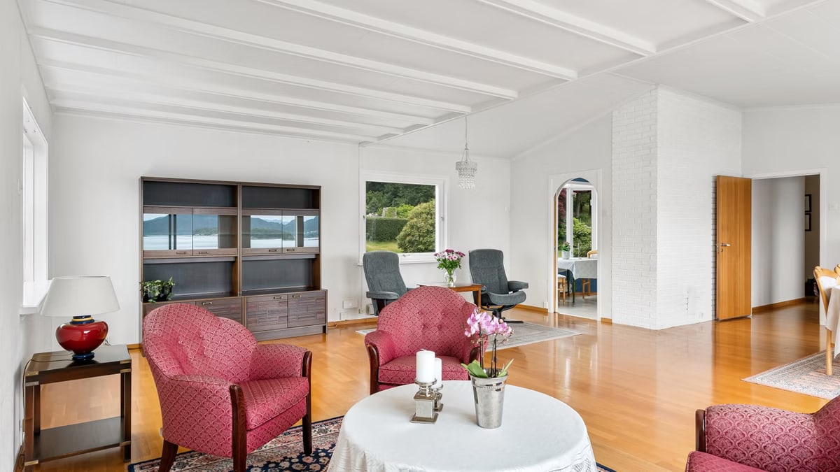 Bright living room with pink armchairs, wooden floors, and picturesque lakeview.